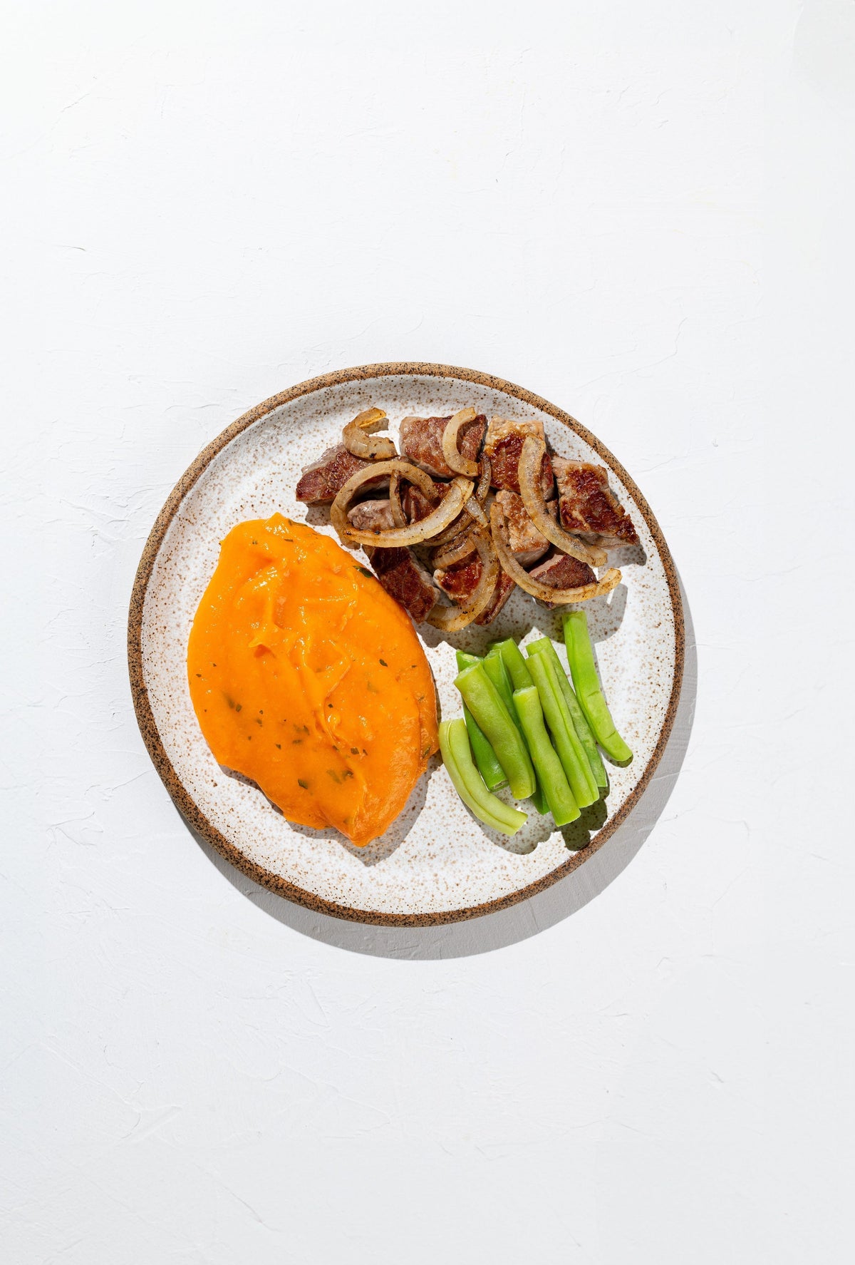 Iscas de carne acebolada com creme de cenoura e vagem salteada